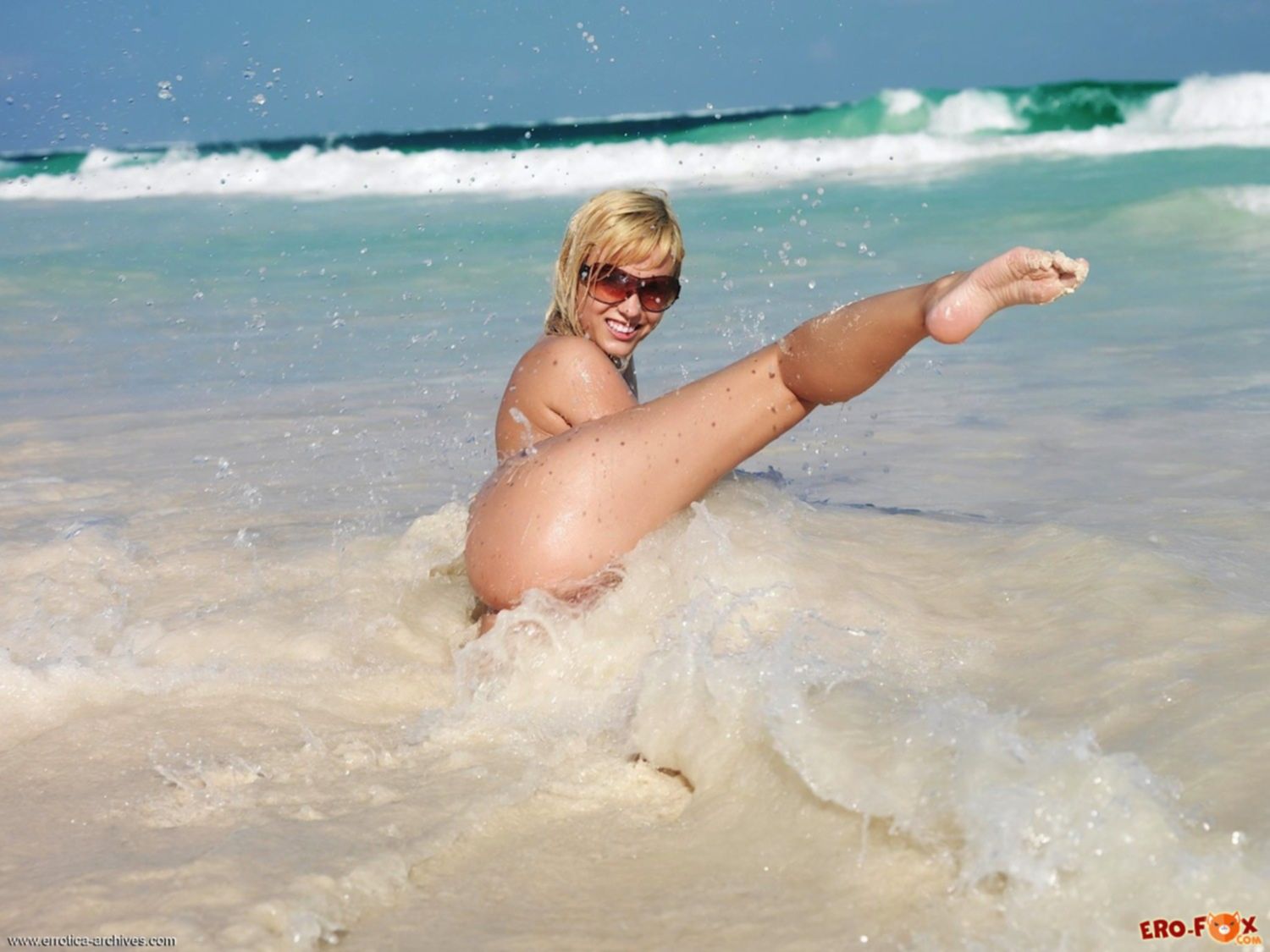 Грудастая голая девка стоит раком на пляже - фото